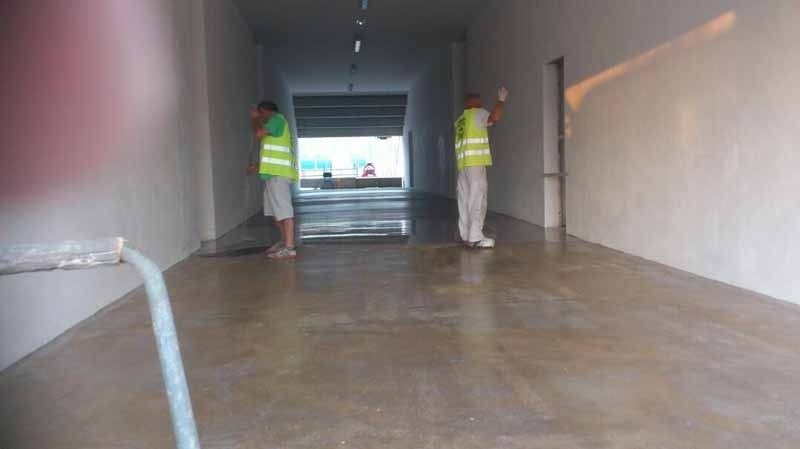 Dos hombres están parados en un pasillo limpiando el piso.