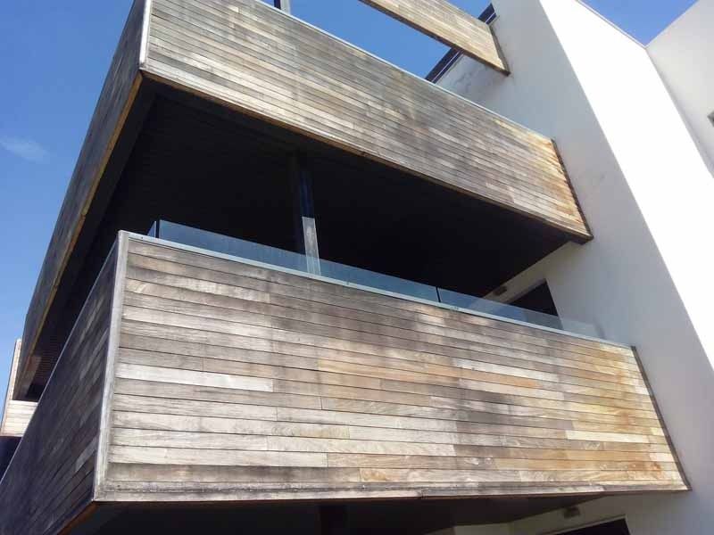 Un balcón en el costado de un edificio con un cielo azul al fondo.