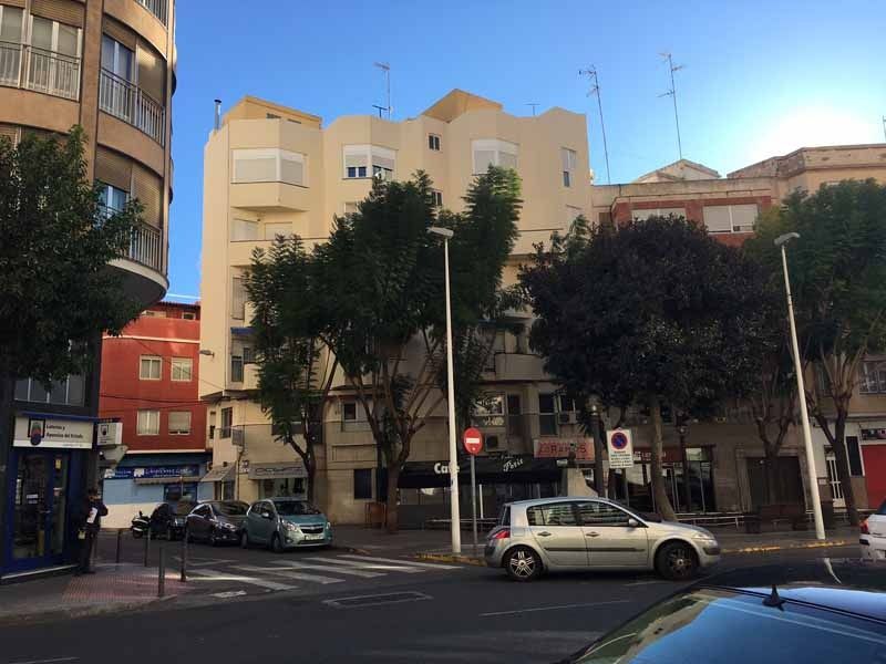Un coche circula por una calle frente a un edificio.