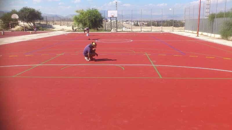 Una persona está arrodillada en una cancha de baloncesto roja.