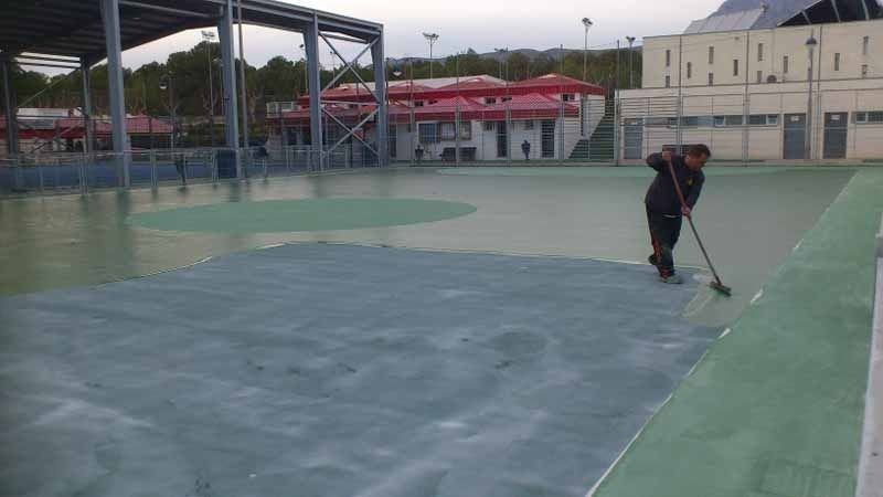 Un hombre está barriendo una cancha de tenis con una escoba.
