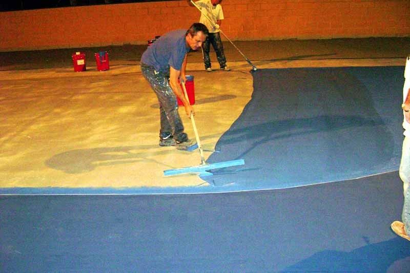 Un hombre está pintando un piso azul con un rodillo.