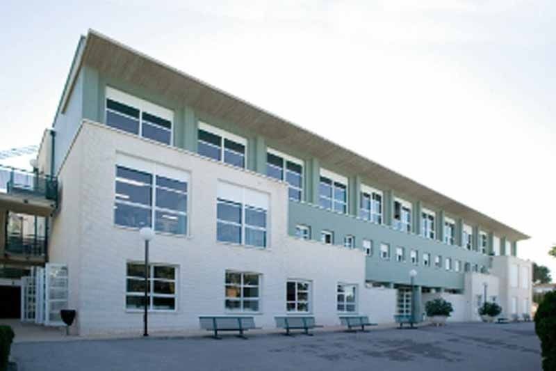 Un gran edificio con muchas ventanas y bancos en el frente.