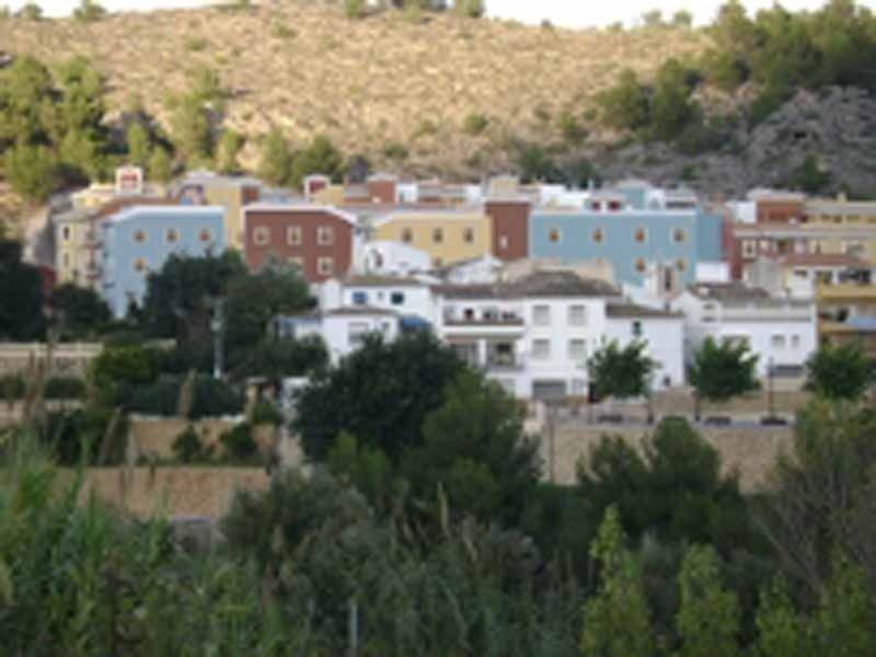 Una hilera de edificios en una ladera con árboles en primer plano