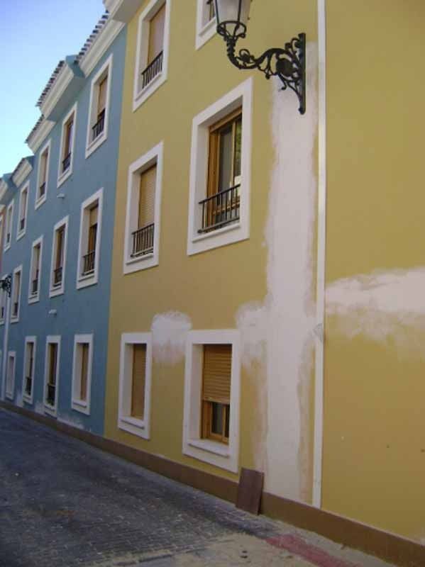 Un edificio amarillo con una lámpara al costado.