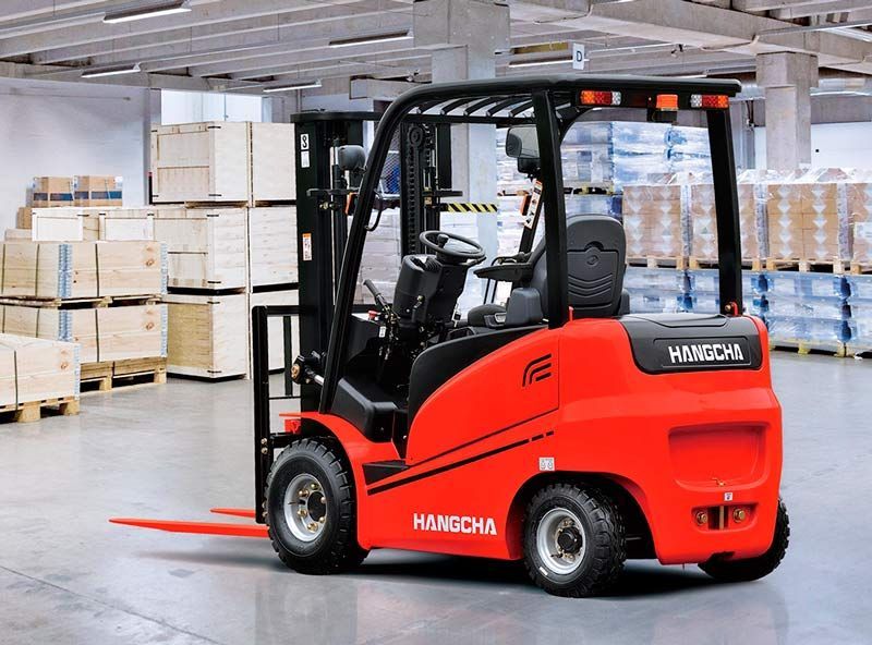 Una carretilla elevadora roja está estacionada en un almacén lleno de cajas.