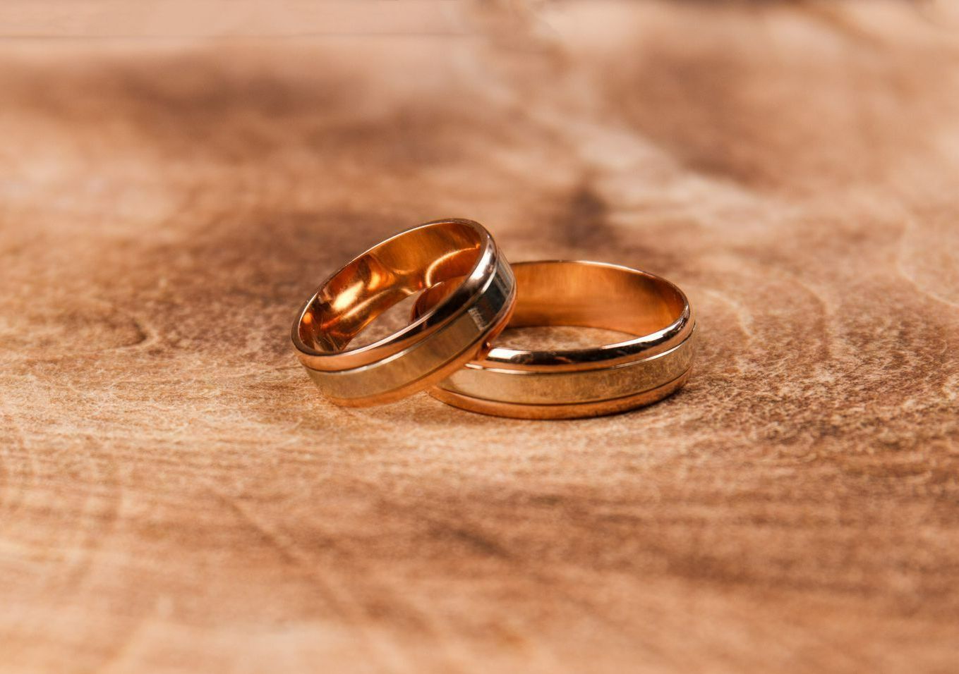 Deux alliances en or sur une surface en bois.