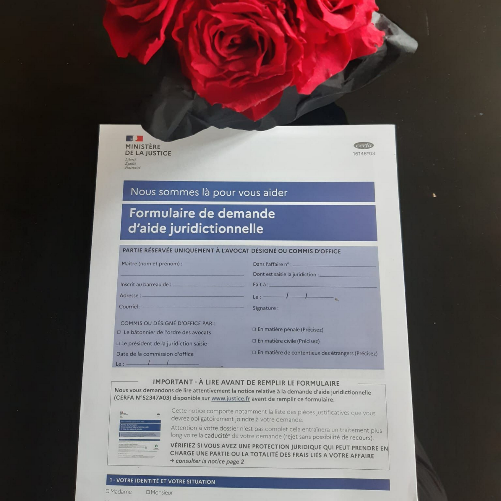 Formulaire d'aide judiciaire sur une table avec des roses rouges en arrière-plan.