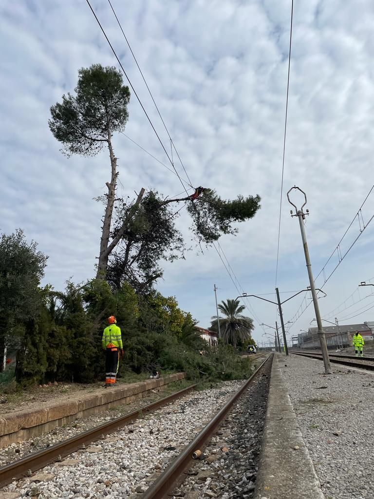 Un hombre con un chaleco amarillo está parado junto a una vía del tren.