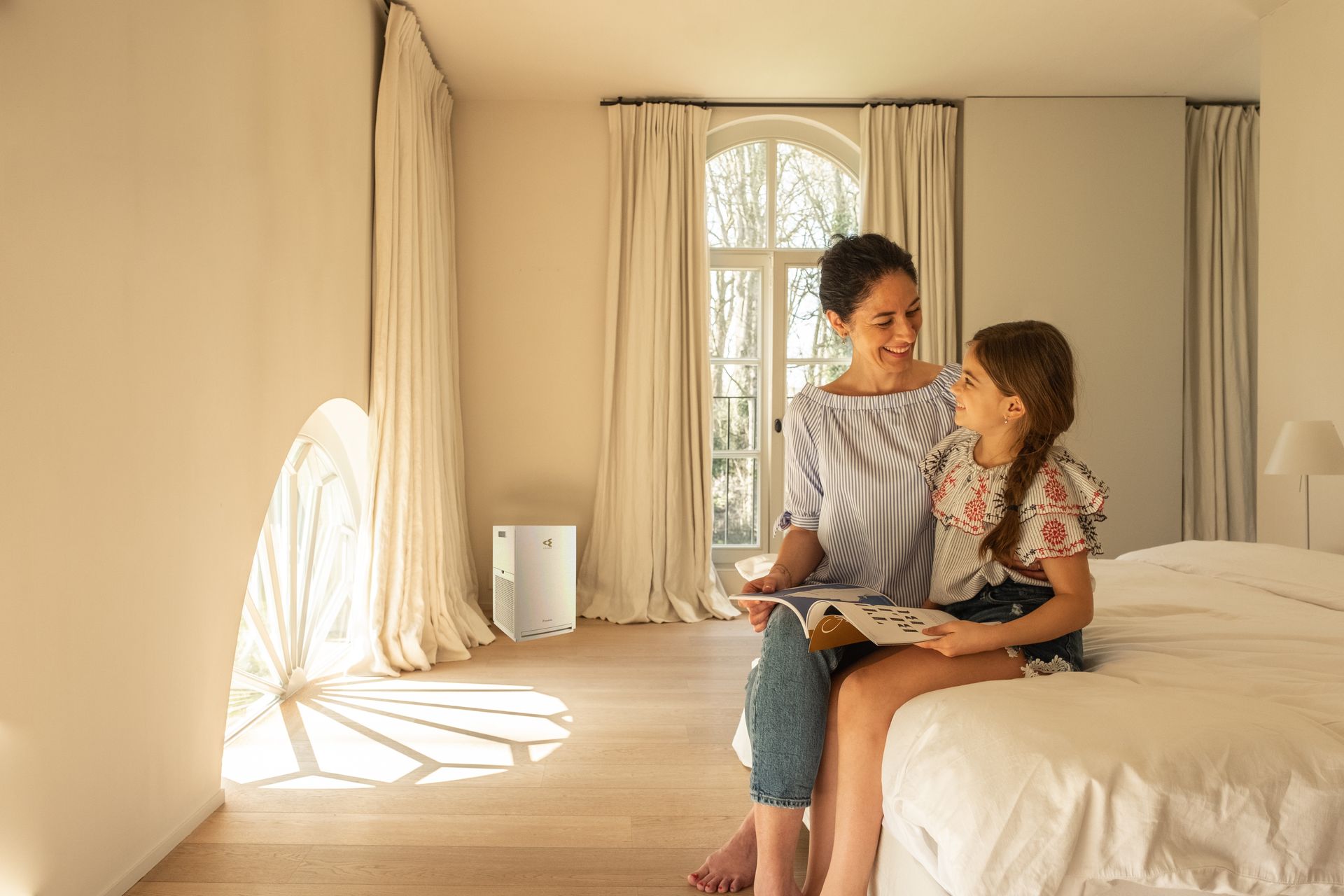 Une mère et sa fille en train de lire dans uen chambre avec un purificateur d'air