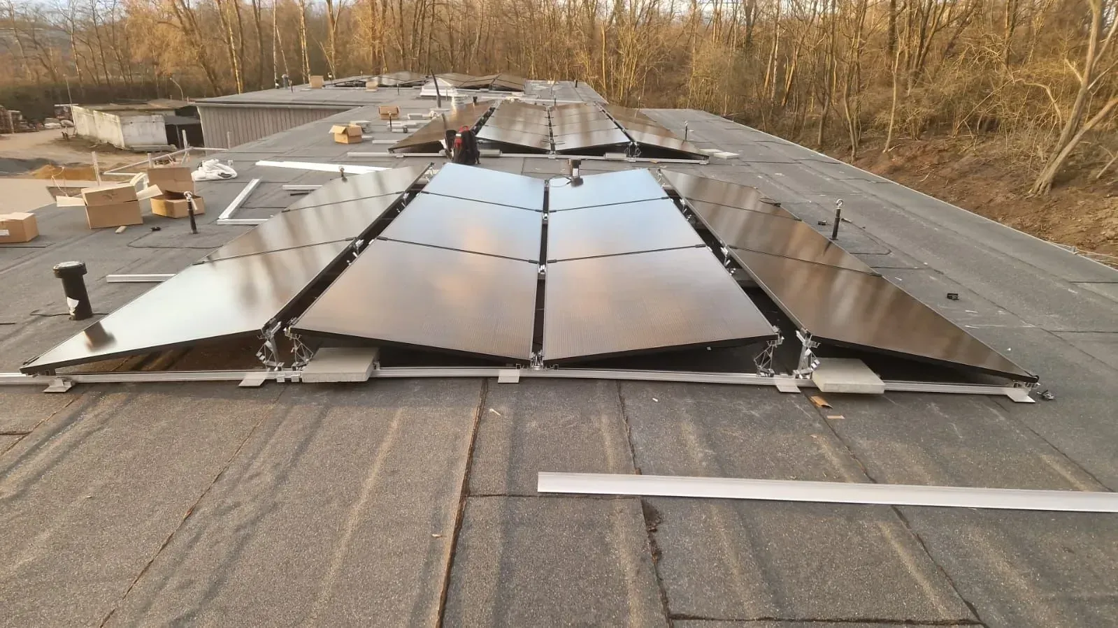 Beschädigte Solaranlage auf einem Dach, mit abgelösten Paneelen und herumliegenden Trümmern.