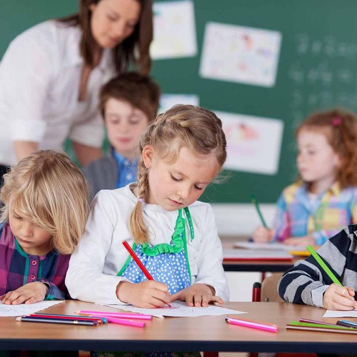 Eine Gruppe Kinder sitzt an Schreibtischen in einem Klassenzimmer.