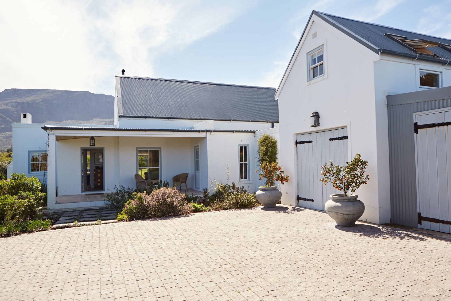 Maison moderne blanche avec garage et cour carrelée baignée de soleil