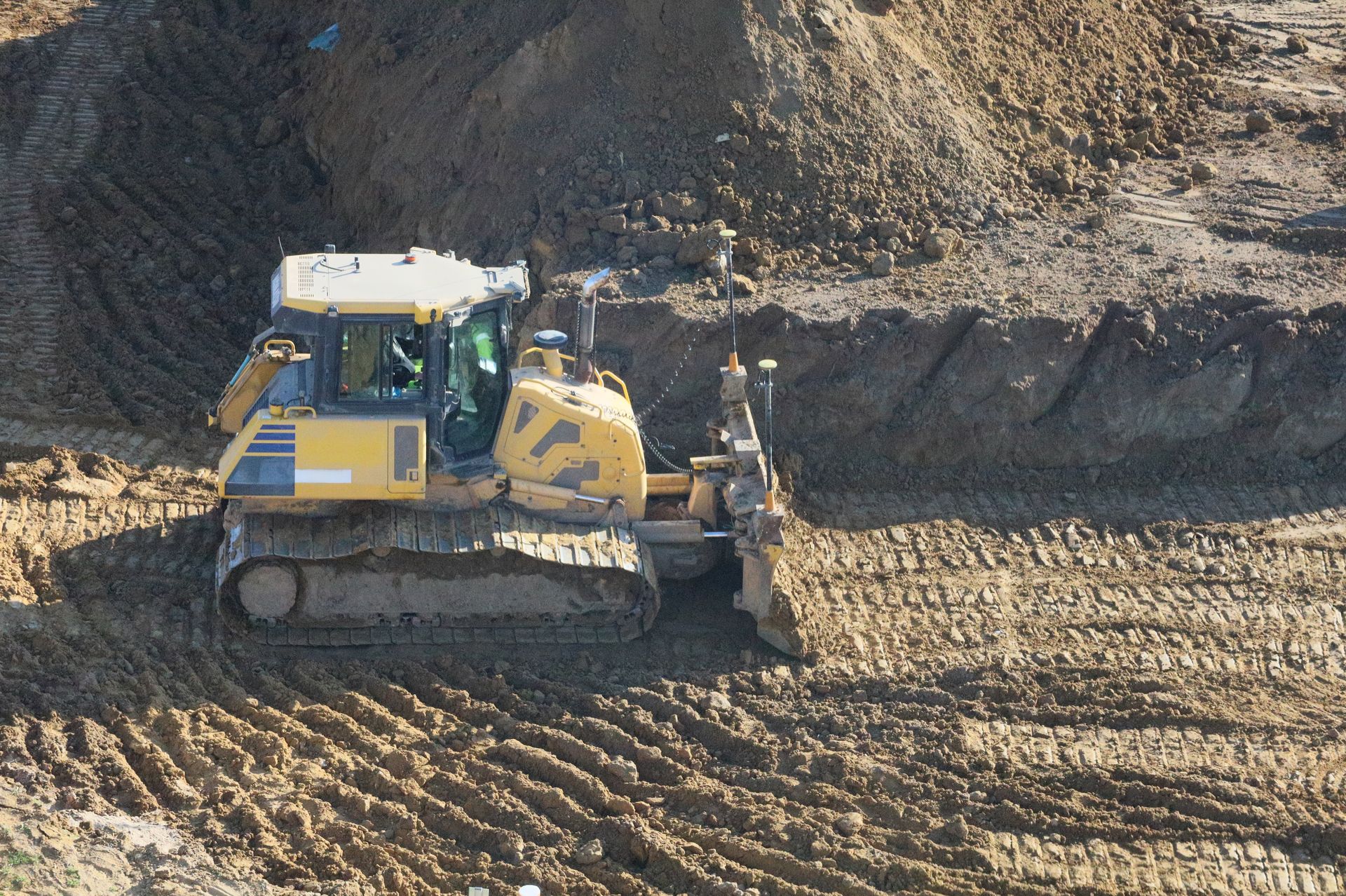 Un bulldozer jaune nivelle la terre sur un chantier rocailleux.