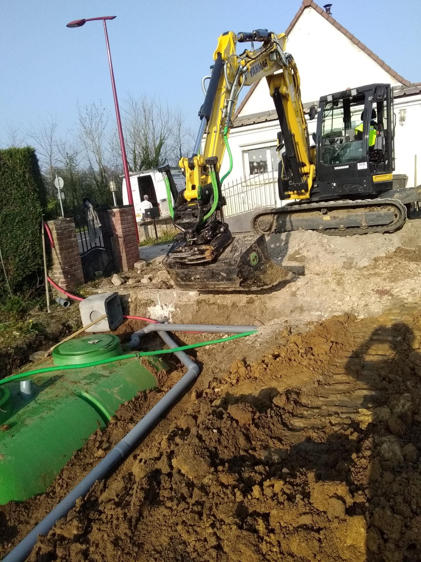 Pelleteuse installant une cuve verte pour assainissement