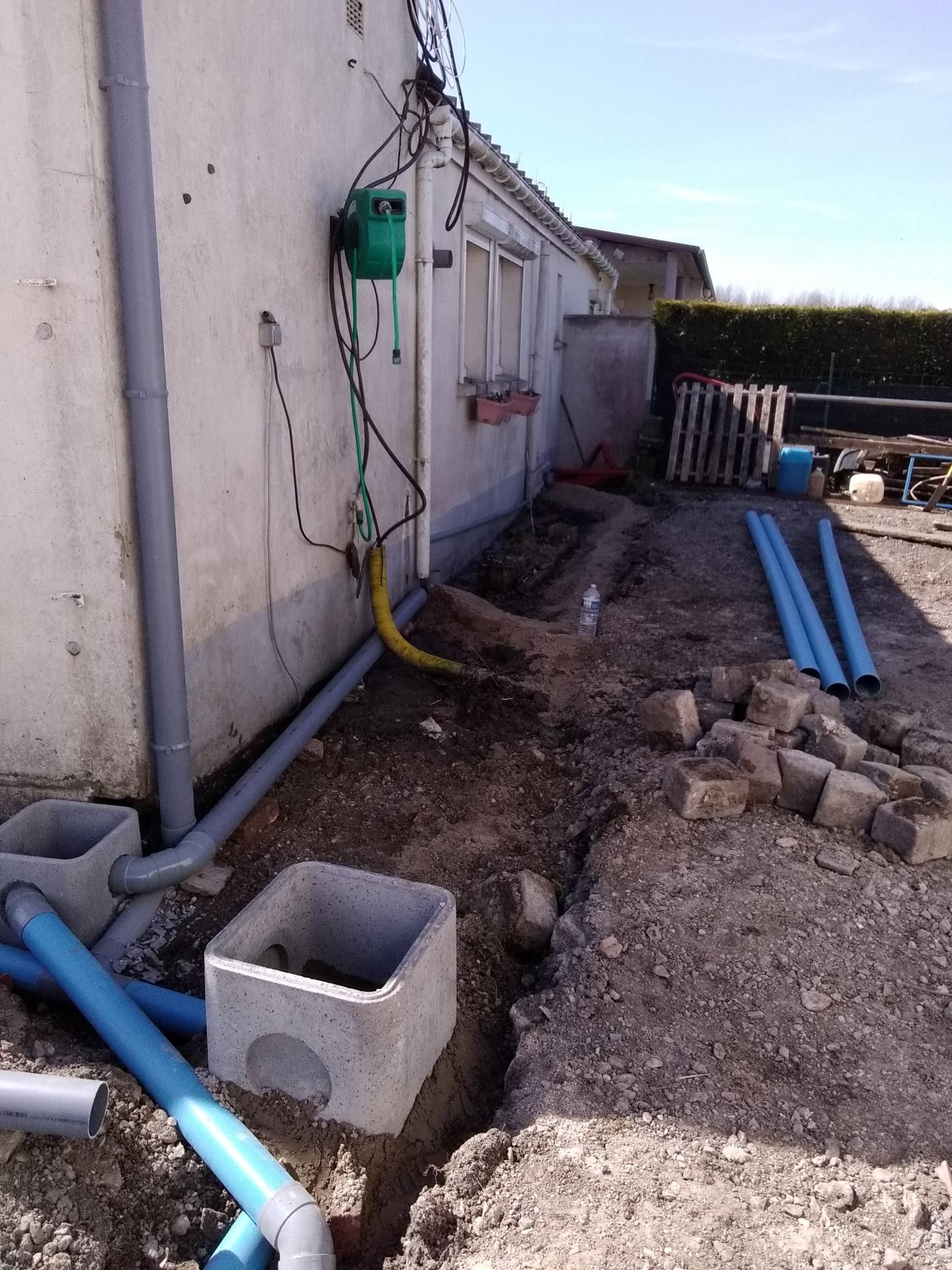 Travaux d’assainissement avec tuyaux bleus et blocs en béton
