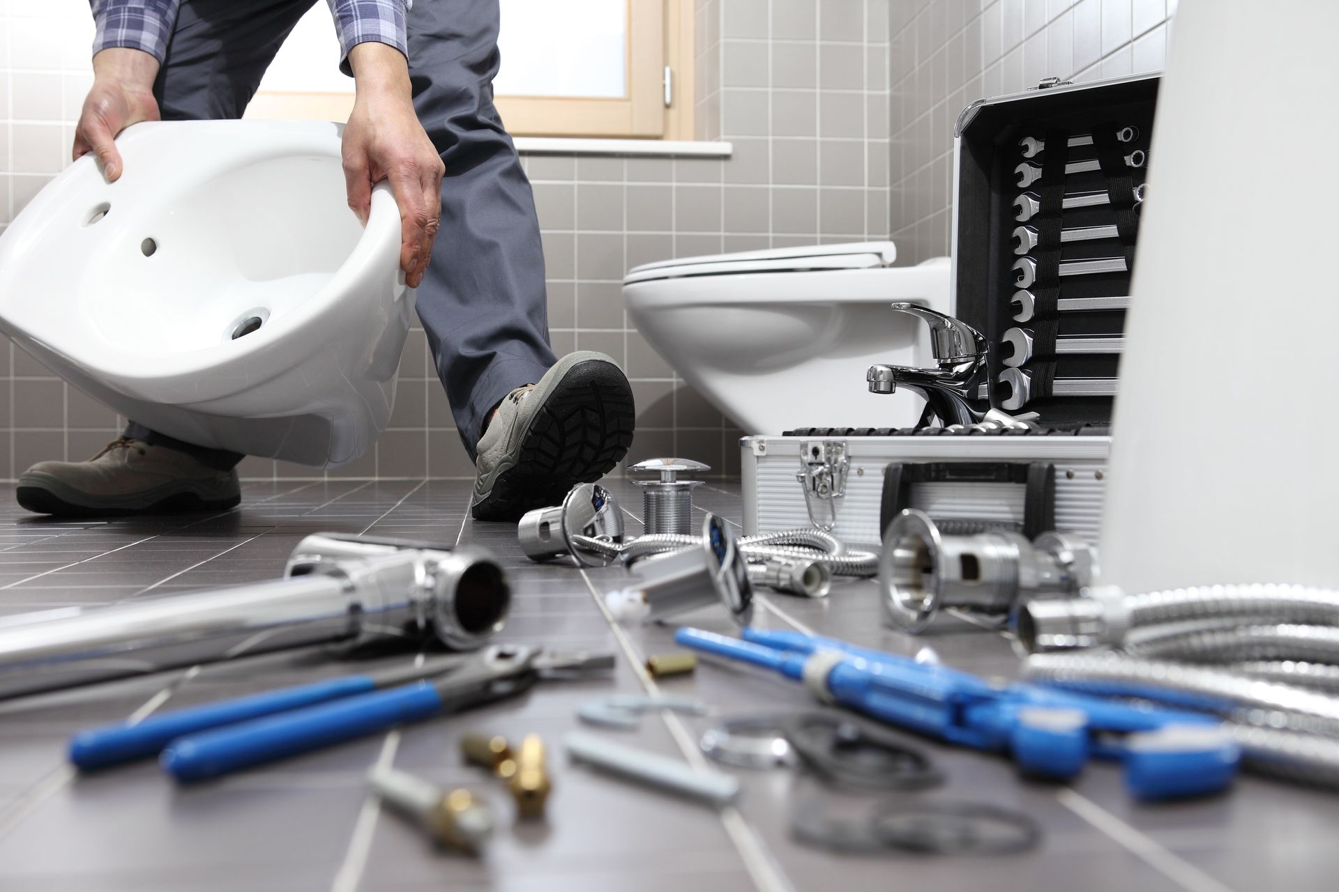 Un plombier installe un WC au milieu d'outils éparpillés lors de la rénovation.