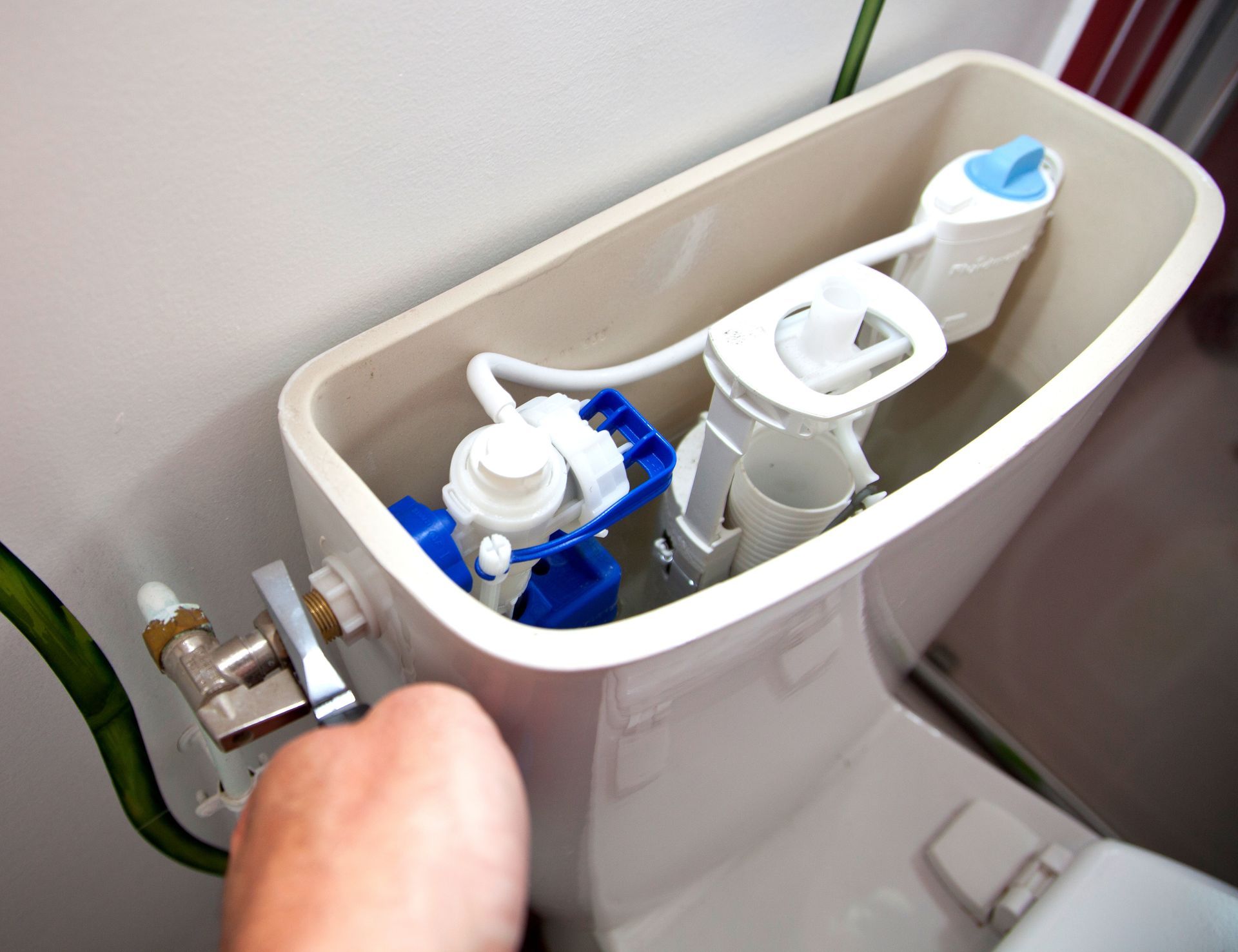 Réservoir de toilette ouvert montrant le mécanisme de chasse d'eau et la valve de remplissage.