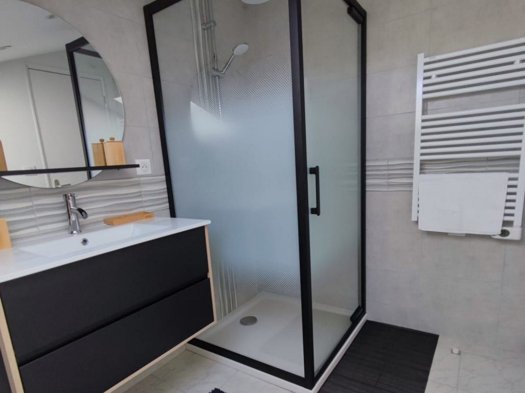 Salle de bains moderne avec meuble-lavabo, miroir et cabine de douche en verre