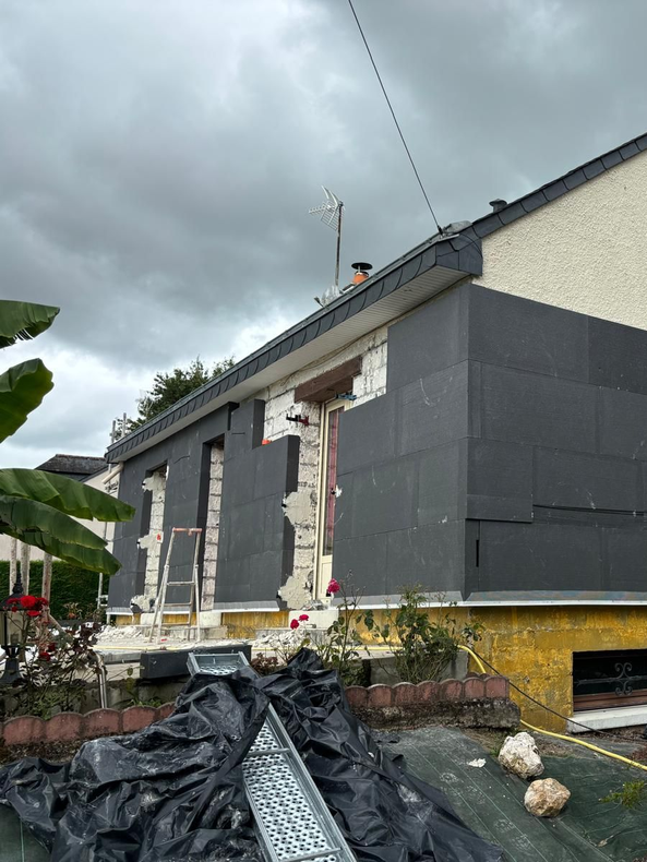 Échafaudages autour de la façade jaune d'un bâtiment avec des garde-corps métalliques et des panneaux d'isolation enveloppés