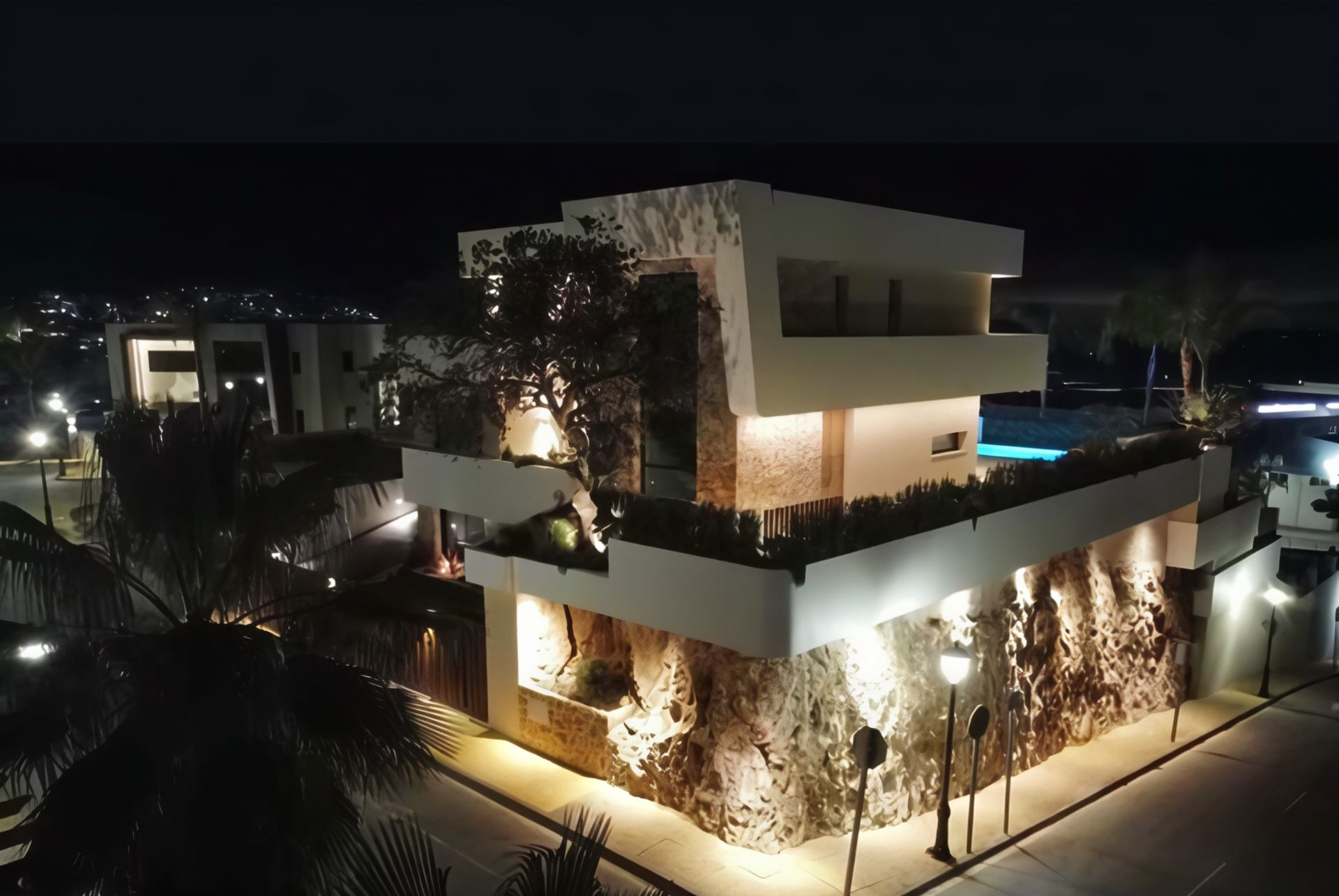 Casa moderna de noche con fachada de piedra e iluminación exterior.