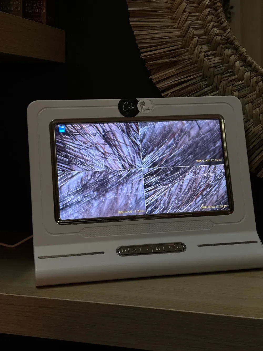 Dispositivo blanco que muestra una vista ampliada del cabello, colocado sobre una superficie de madera.
