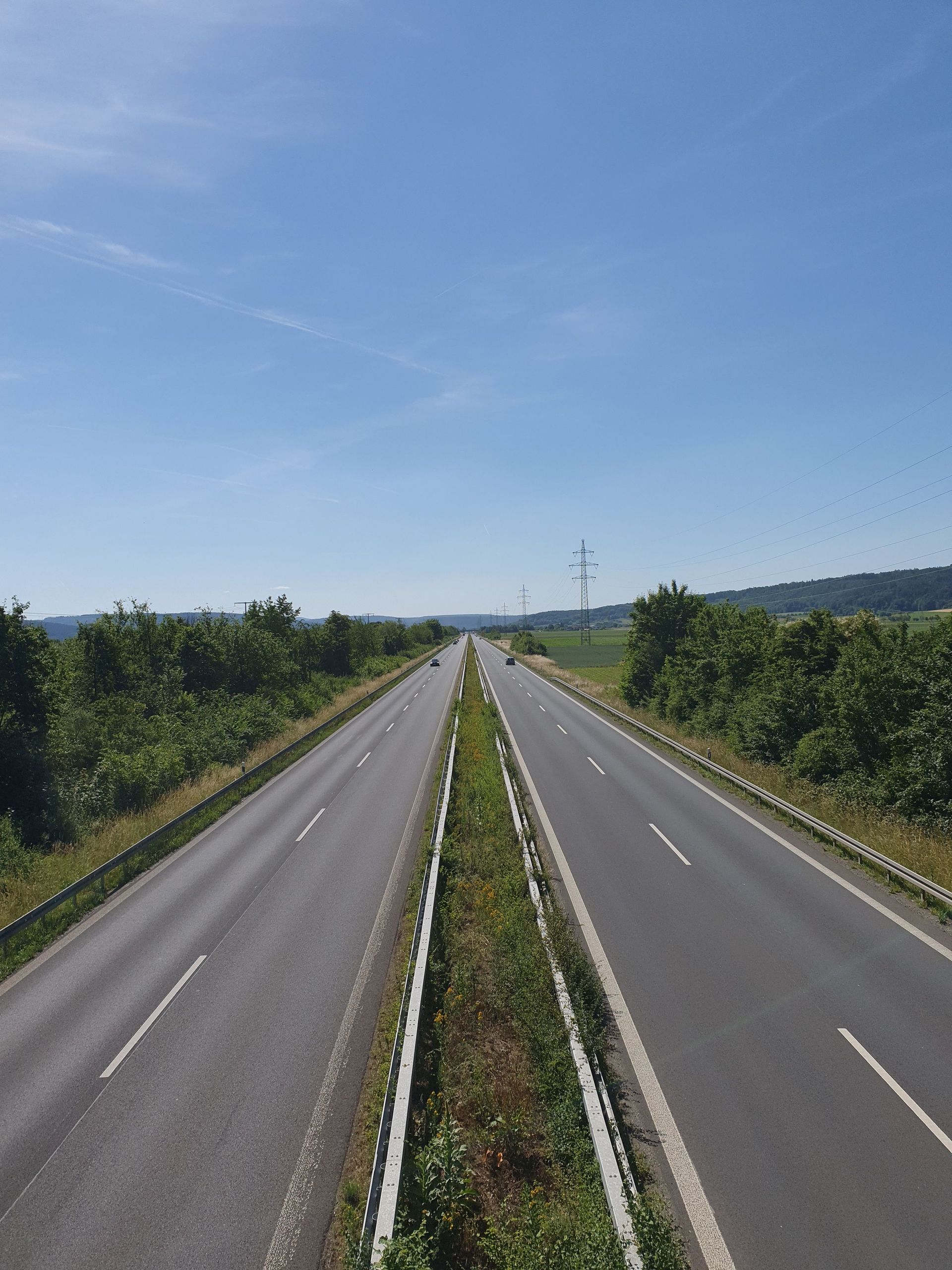 Una autopista vacía de doble calzada que se extiende hasta el horizonte bajo un cielo azul despejado