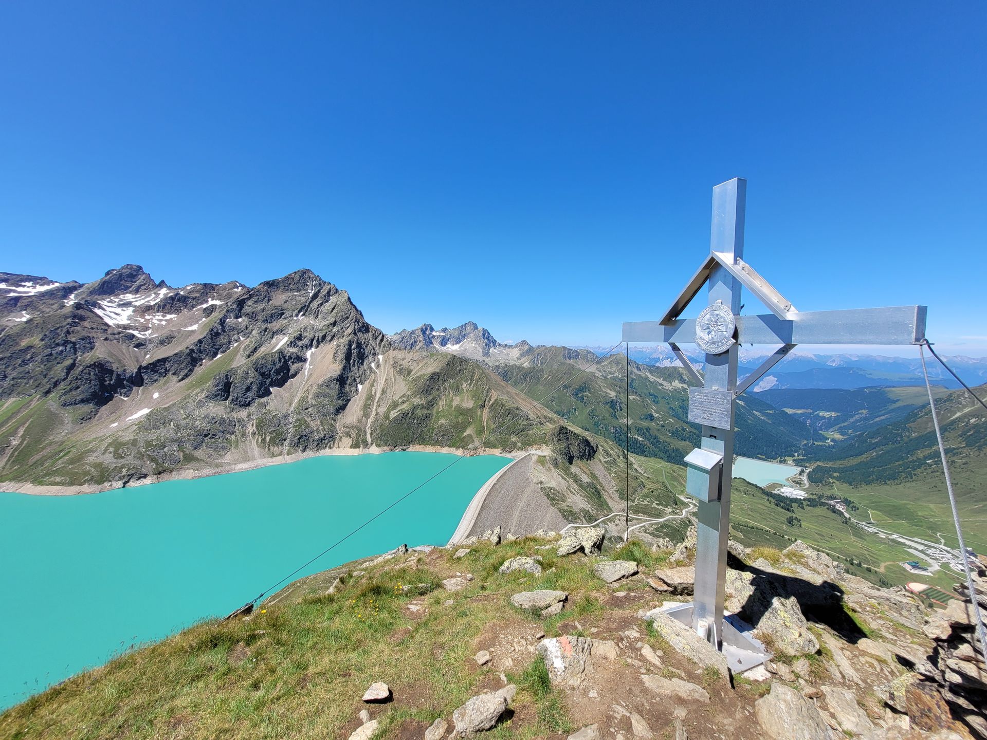 Schreibtisch mit Laptop, Monitor, Notebook, Maus, Pflanzen am Fenster.