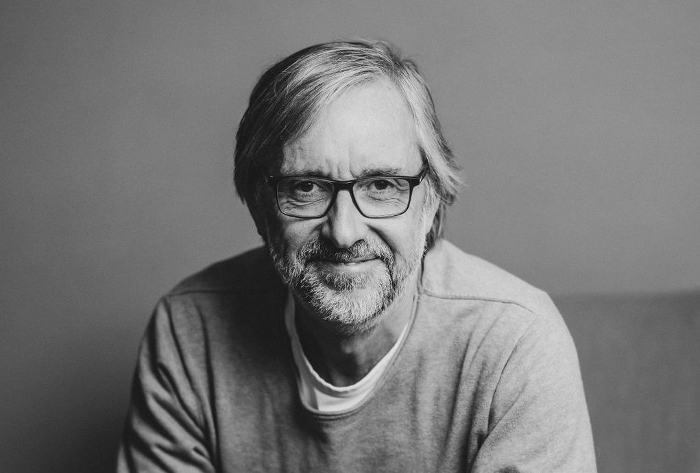 Älterer Mann mit Brille und Bart lächelt und schaut direkt in die Kamera.