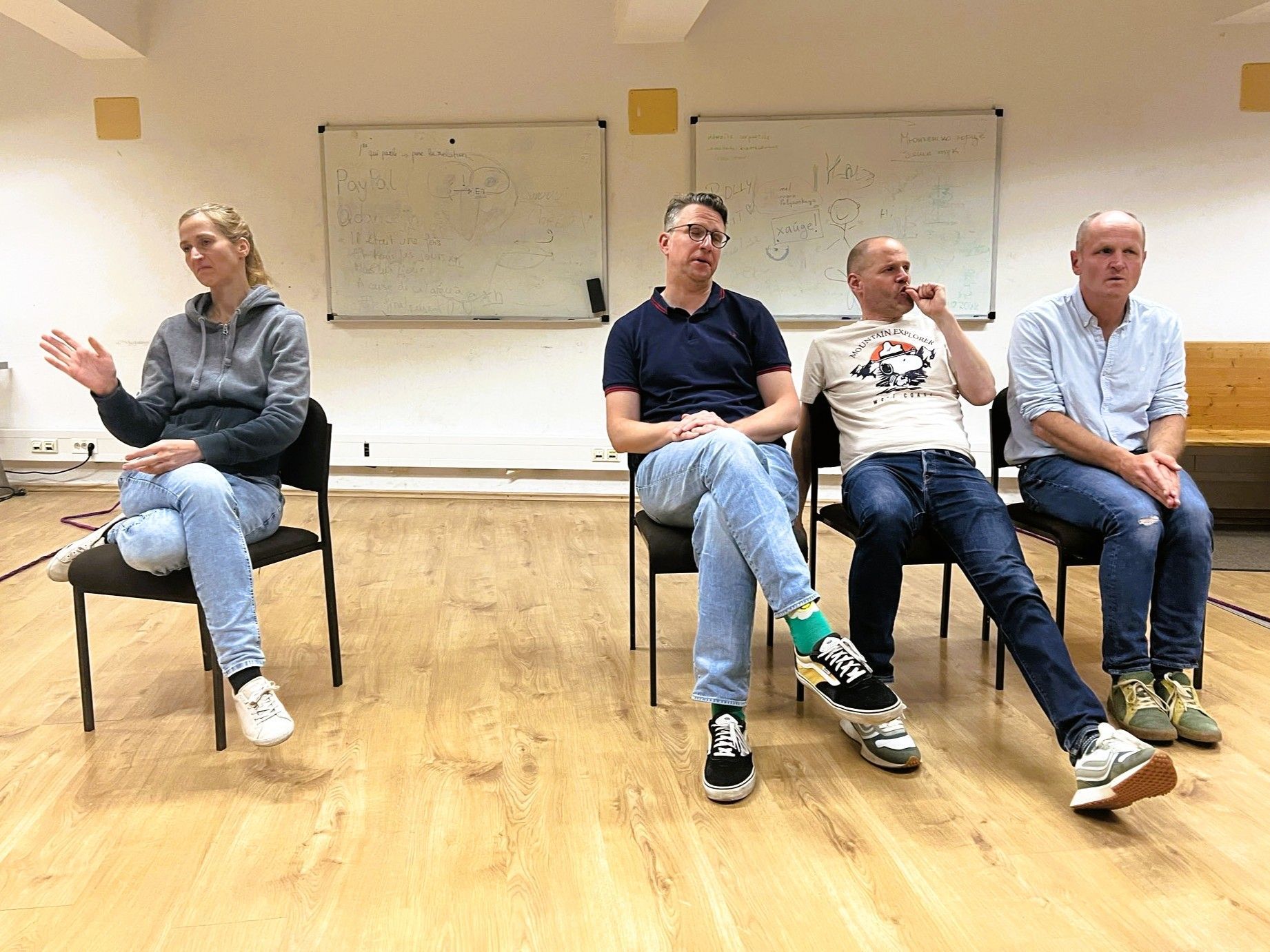 Menschen bei einer Präsentation in einer Kunstgalerie mit einer Projektionsleinwand und Fotografien an der Wand.