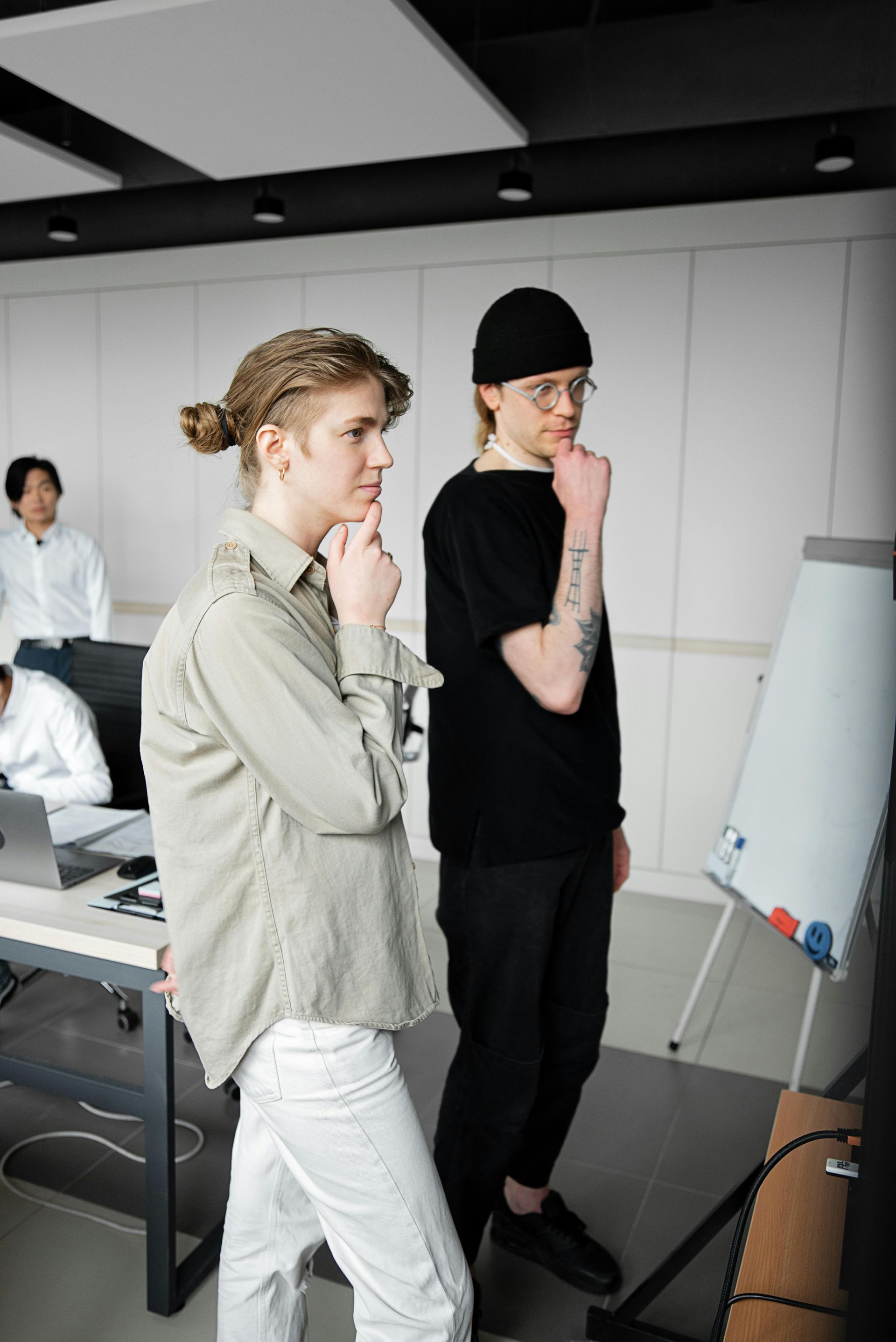 Eine Person schreibt an einem Schreibtisch auf einem Notizblock und interviewt eine Person in blauem Hemd und Krawatte.