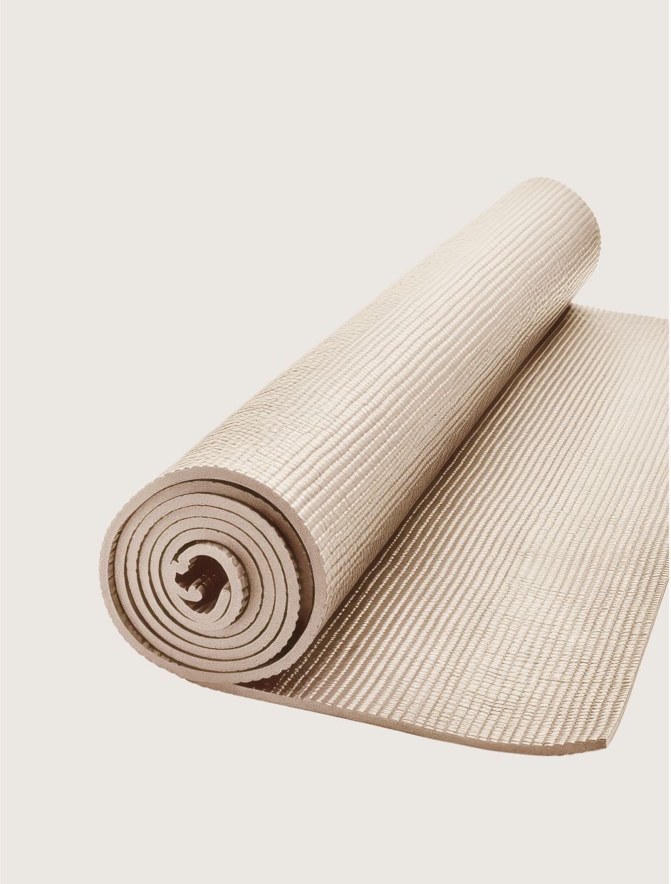 Aufgerollte beige Yogamatte auf cremefarbenem Hintergrund.