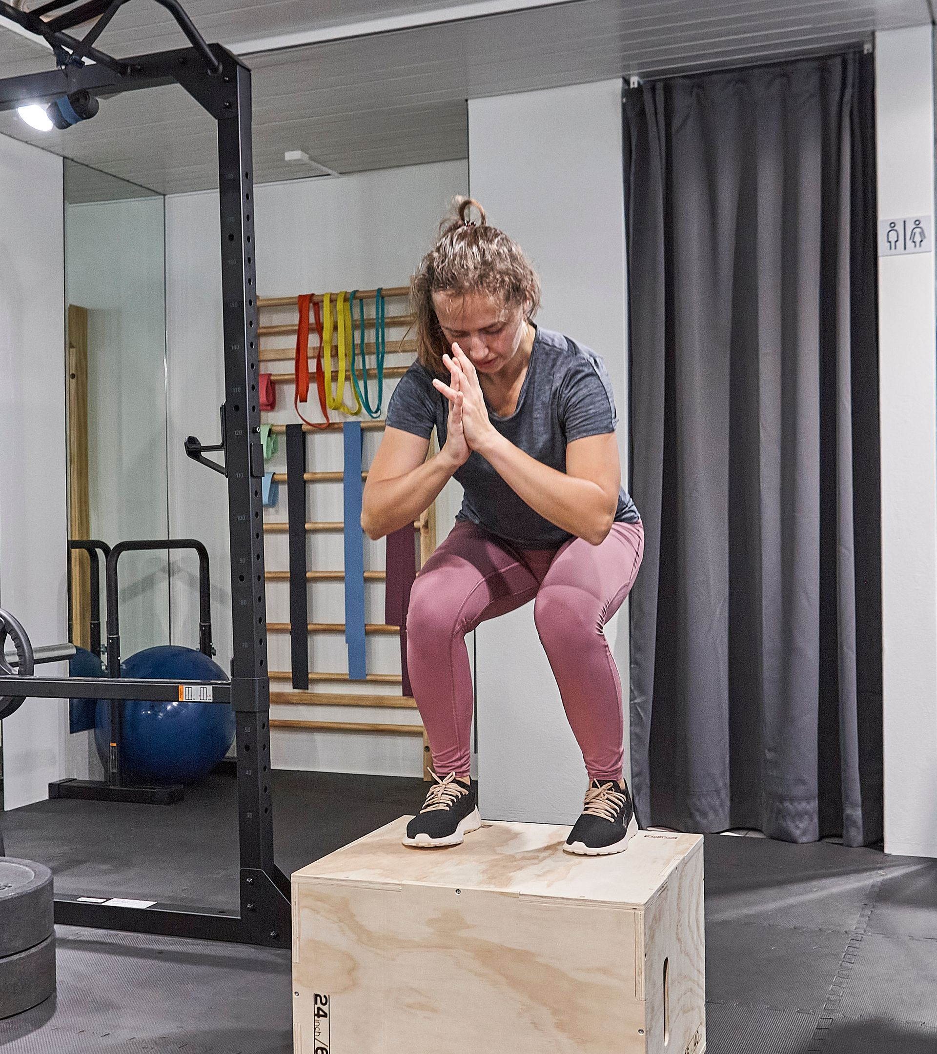 Ein hell erleuchteter Physiotherapie- oder Massageraum mit einer blauen Behandlungsliege, einem kleinen Hocker, einem anatomischen Skelett und einem Schreibtisch.
