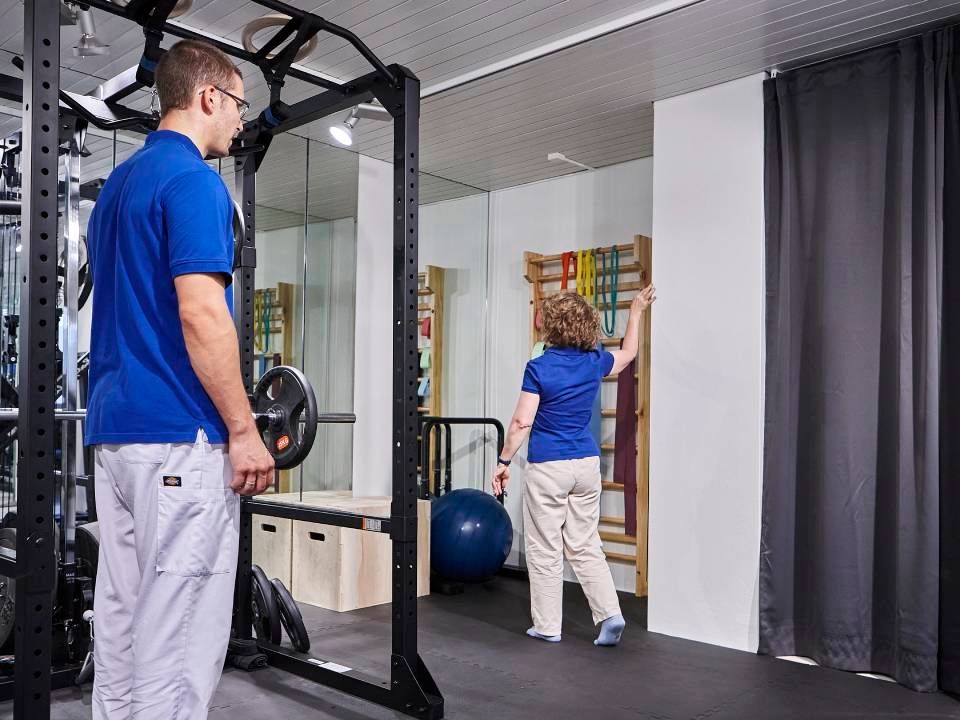 Ein Profi leitet eine Person durch Physiotherapieübungen in einem Fitnessstudio.