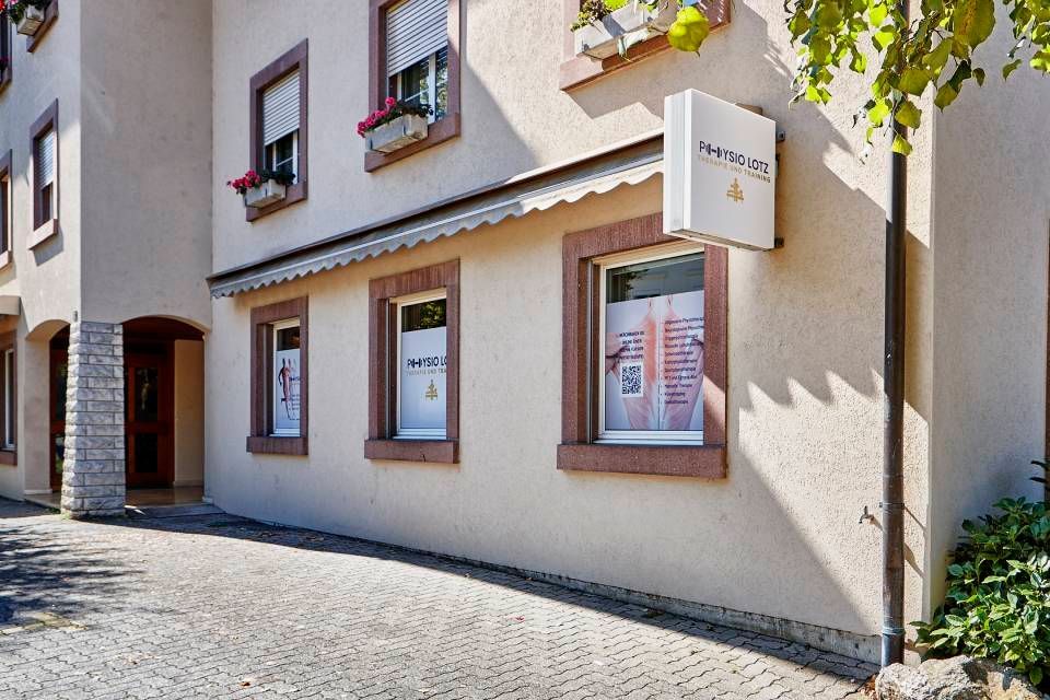 Ein hellfarbiges, zweistöckiges Gebäude mit mehreren Fenstern, Backsteinverzierungen und einem auffälligen Schild mit der Aufschrift „NEMESIS“ am Eingang.