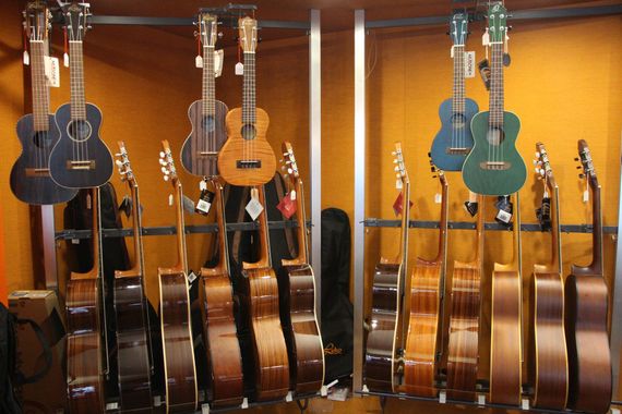 Innenansicht eines Gitarrenladens mit hängenden Akustikgitarren und einer Person, die im Hintergrund stöbert.