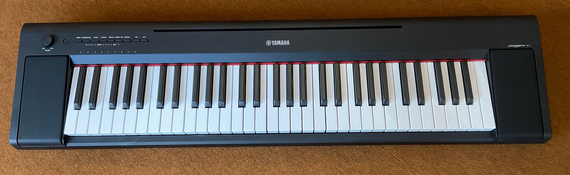 Schwarze elektronische Tastatur auf braunem Teppich, von oben betrachtet.