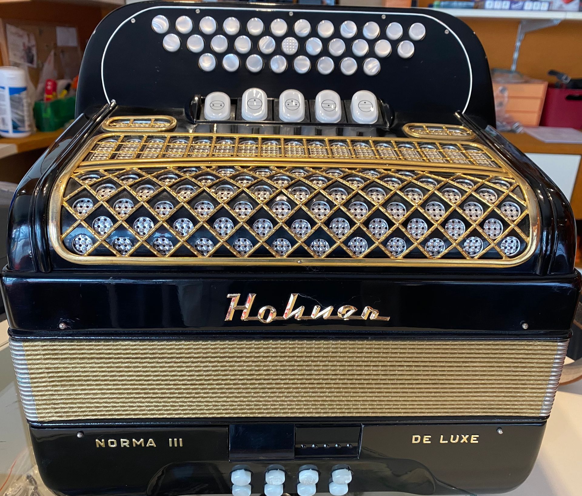 Schwarzes und goldenes Hohner Norma III De Luxe Akkordeon mit verziertem Gitter und weissen Knöpfen