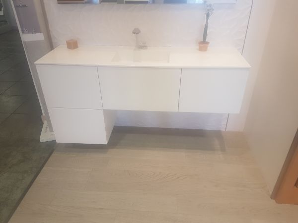 Mueble de baño blanco de pared con tres cajones y un mueble auxiliar. Grifo plateado y dos macetas pequeñas encima.