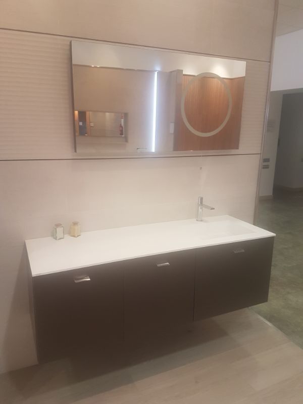 Baño moderno con tocador flotante de color marrón oscuro, encimera blanca, espejo grande y un solo grifo.