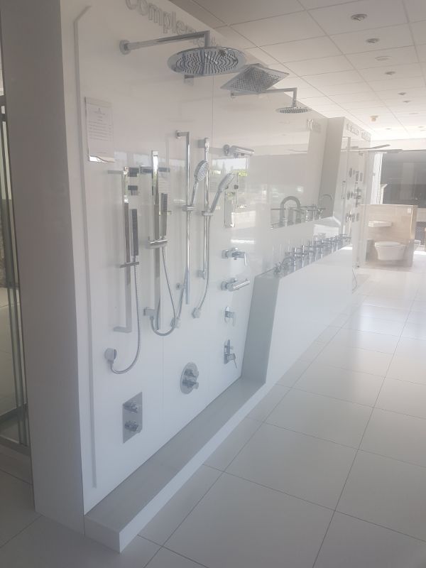 Exhibición en sala de exposición blanca de varios cabezales de ducha y grifos.