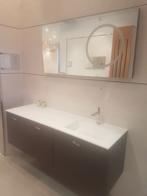 Baño con tocador largo de color marrón oscuro, encimera blanca y espejo grande.