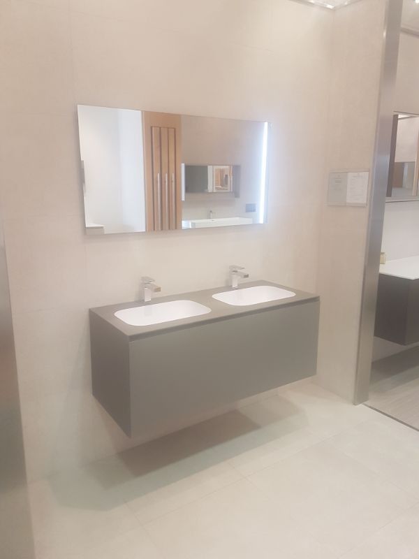 Un baño moderno con un tocador doble flotante gris, dos lavabos blancos y un gran espejo iluminado.