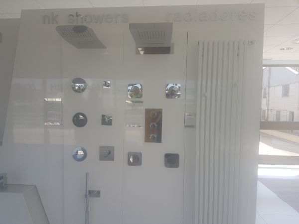 Exposición en sala blanca de cabezales de ducha y grifería con radiador.