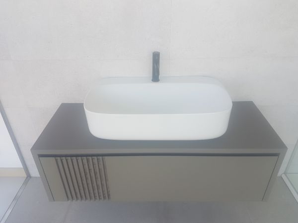 Mueble de baño gris y blanco con lavabo rectangular y grifo oscuro.