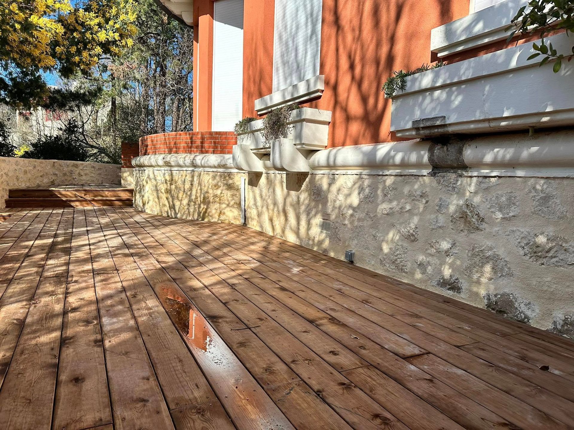 Application d'un enduit texturé brun clair sur un mur.