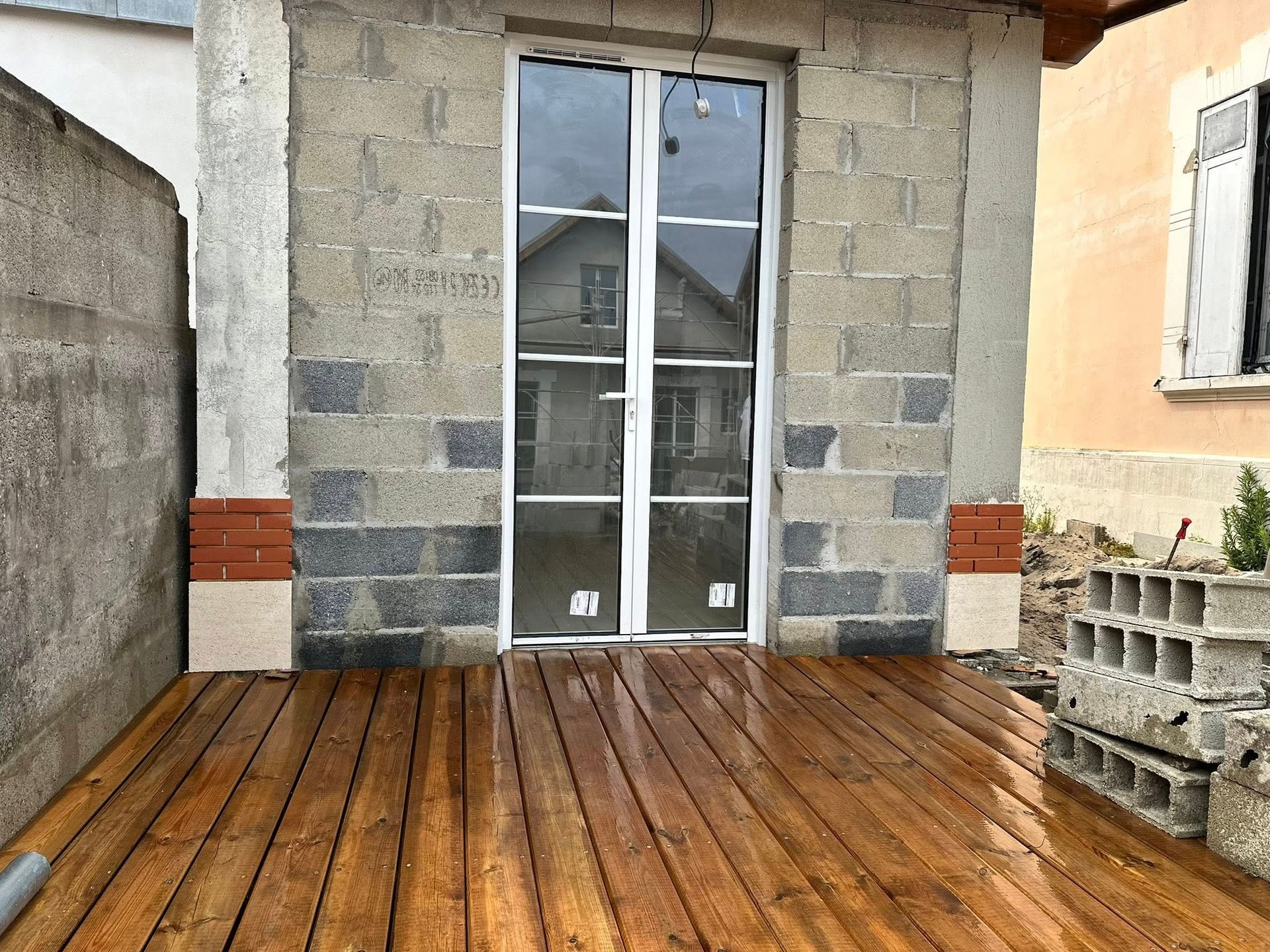 Une double porte vitrée encastrée dans un mur en parpaings