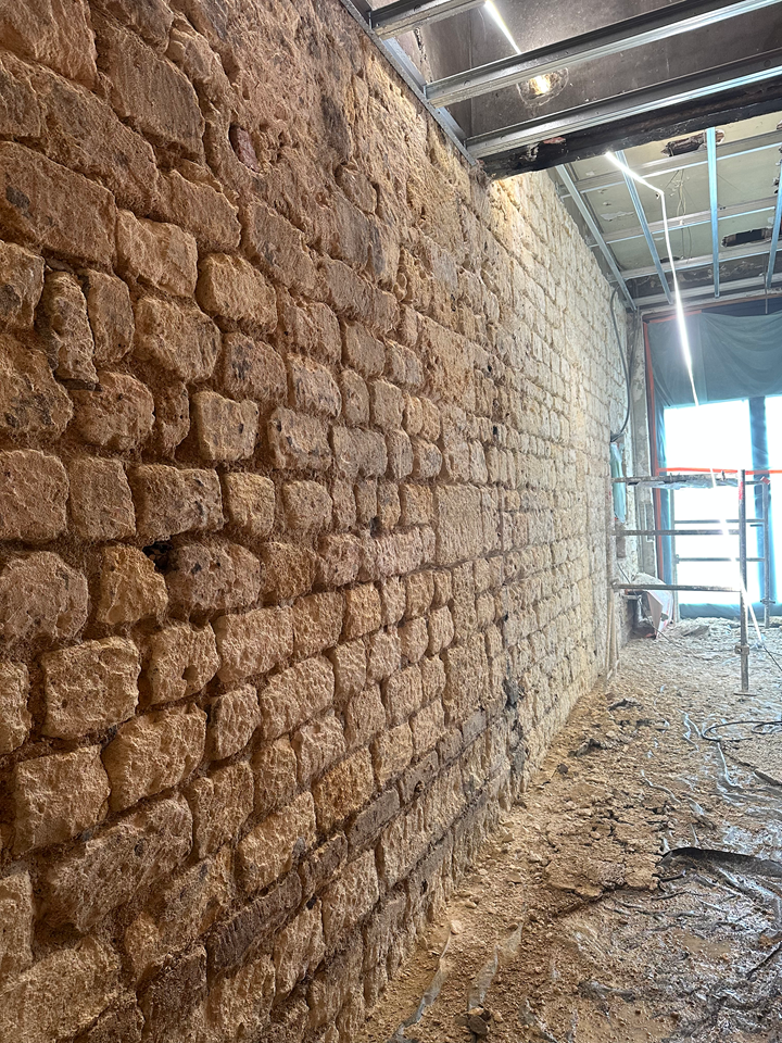 Un long mur apparent de blocs de maçonnerie bruts de couleur beige