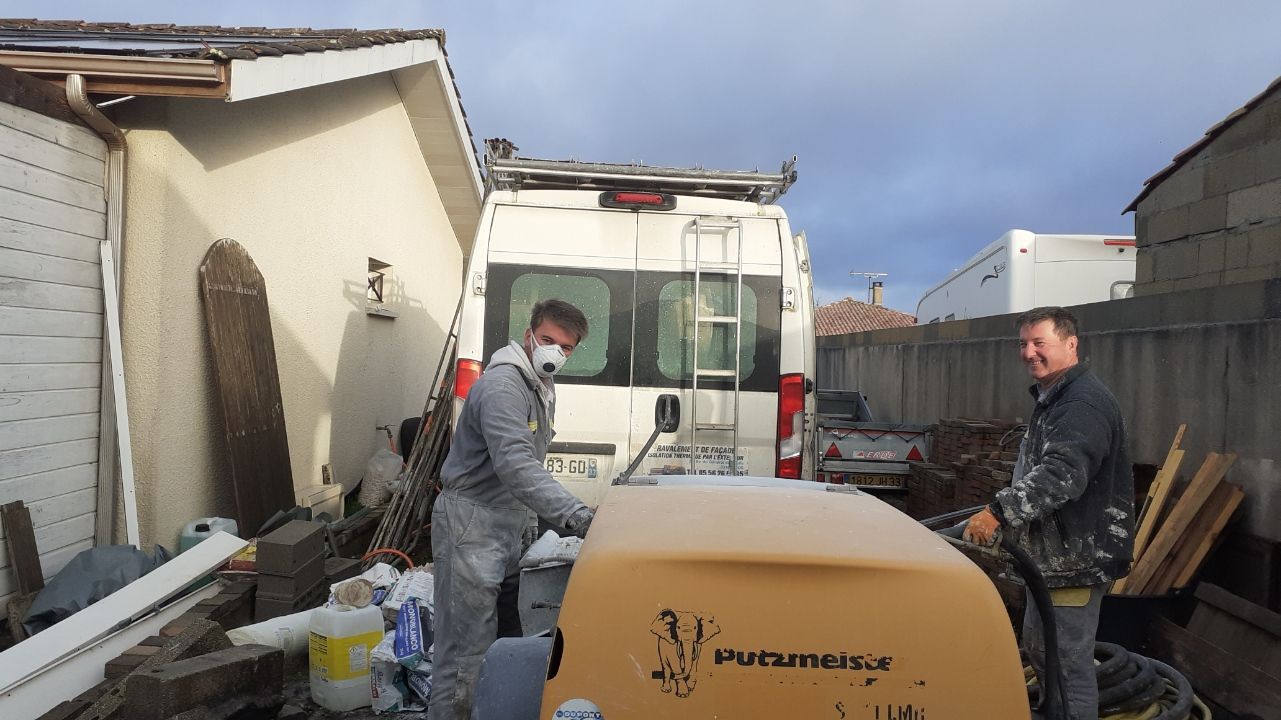 Deux personnes en tenue de travail manœuvrent une machine industrielle.