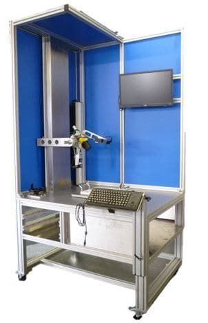 Industrieroboterarm in einer blauen Testkabine mit Monitor und Metallarbeitstisch